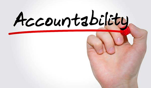 A hand underlining the word "Accountability" written in black marker on a white background.
